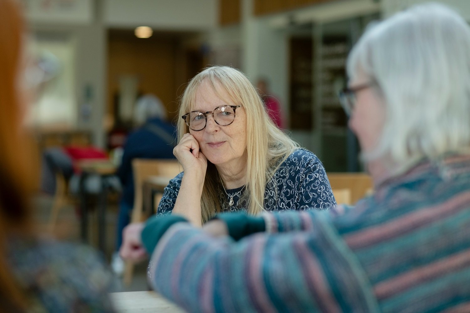 Woman leaning on hand talking to another woman in the foreground
